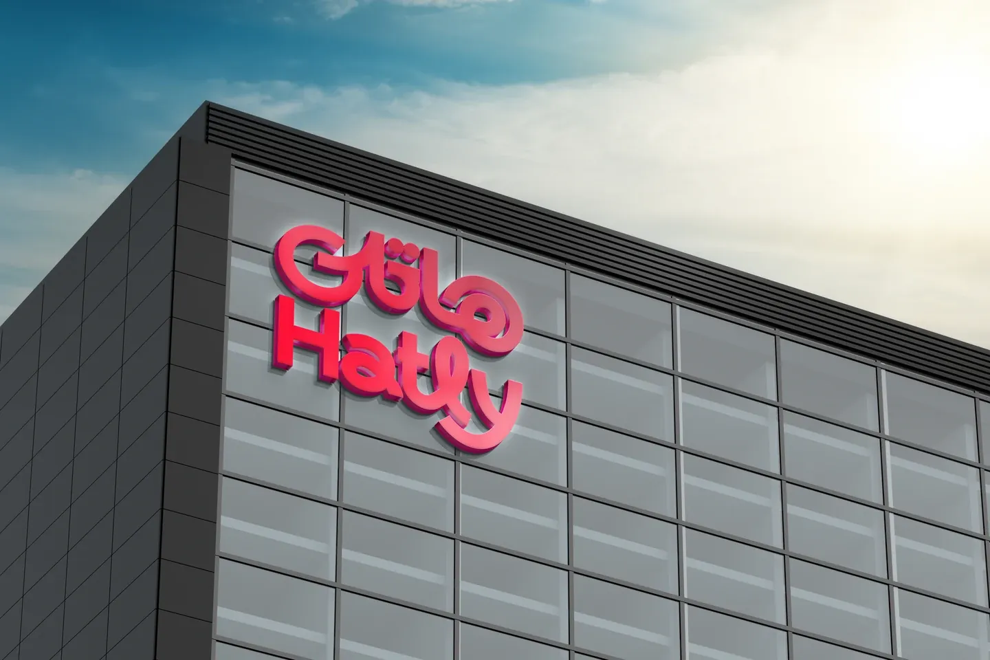 Raised red bilingual Hatly lettering on a gray building facade