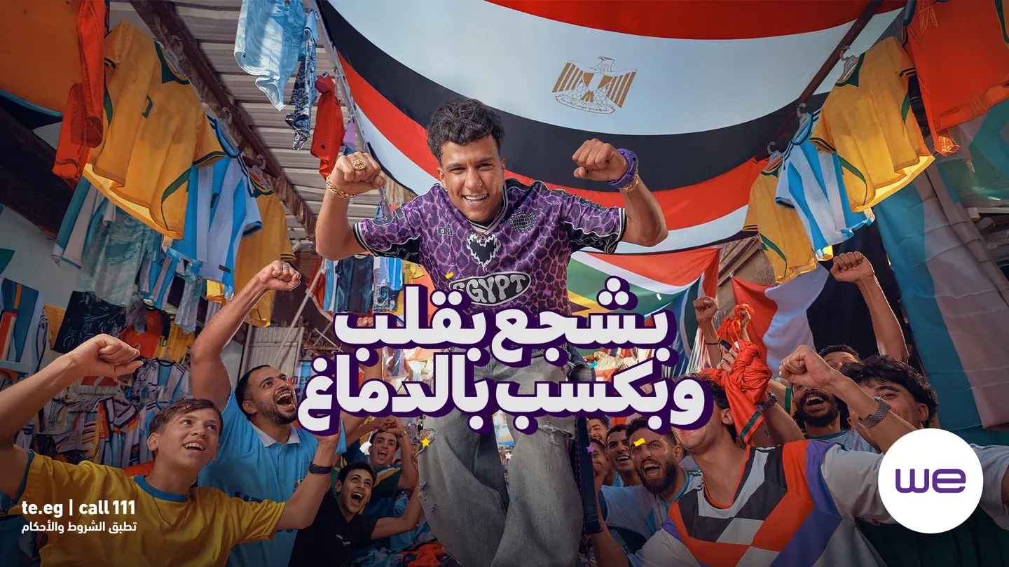 WE campaign artwork with cheering football fans, an Egyptian flag, a man in a purple jersey and a white Arabic headline