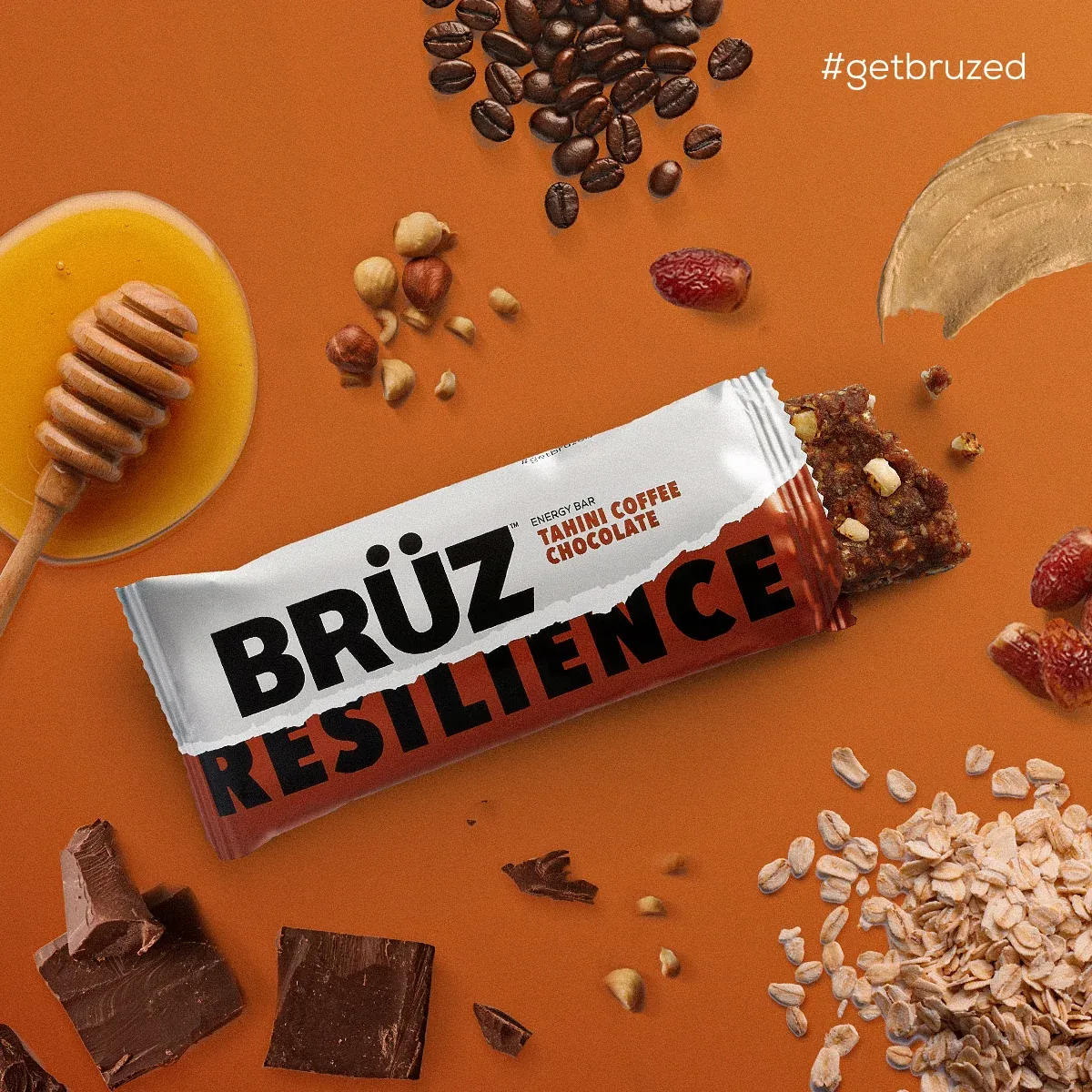 BRÜZ Resilience bar surrounded by honey, nuts, coffee beans and chocolate on orange