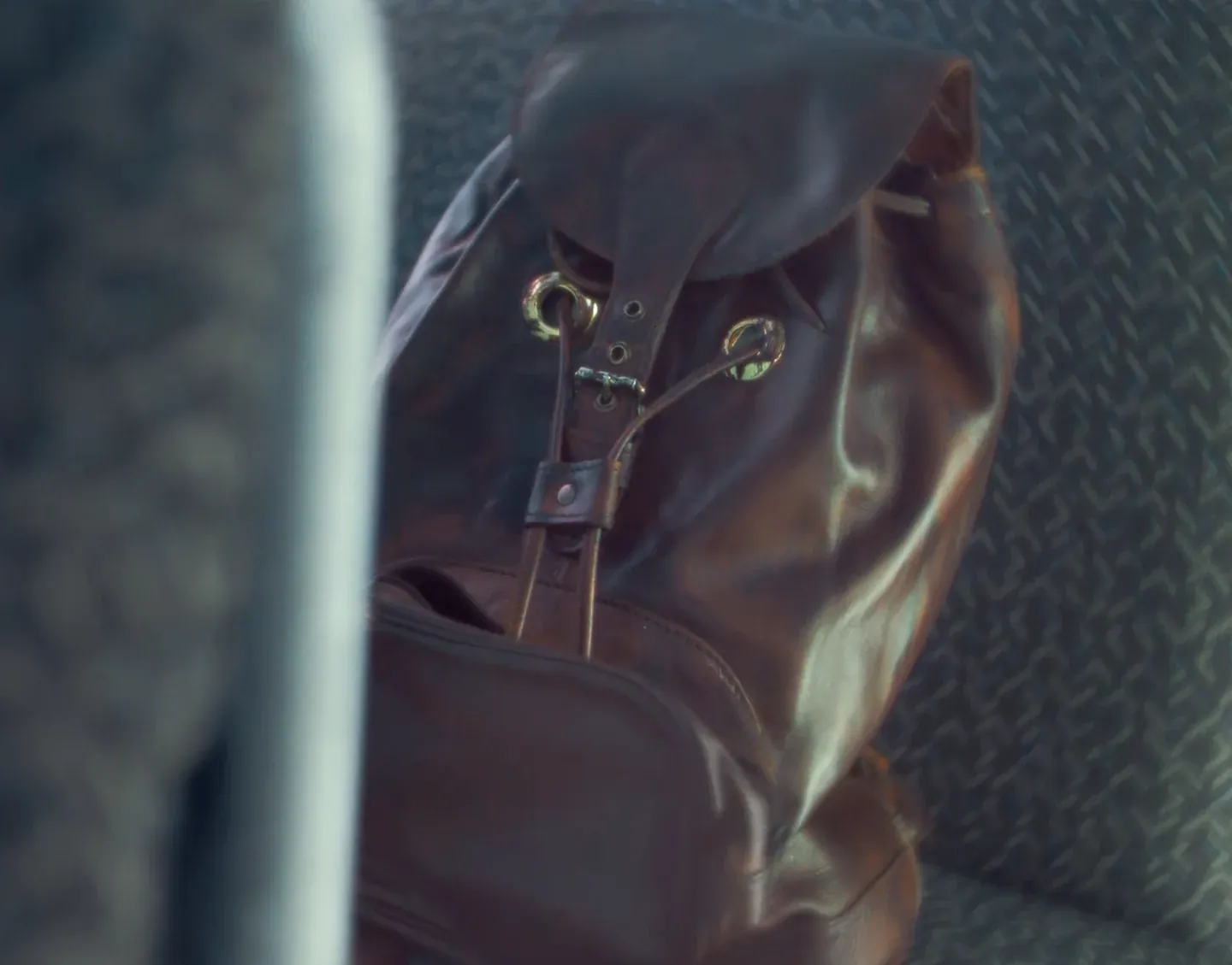Brown leather drawstring backpack on a bus seat in the Spotify Bus film