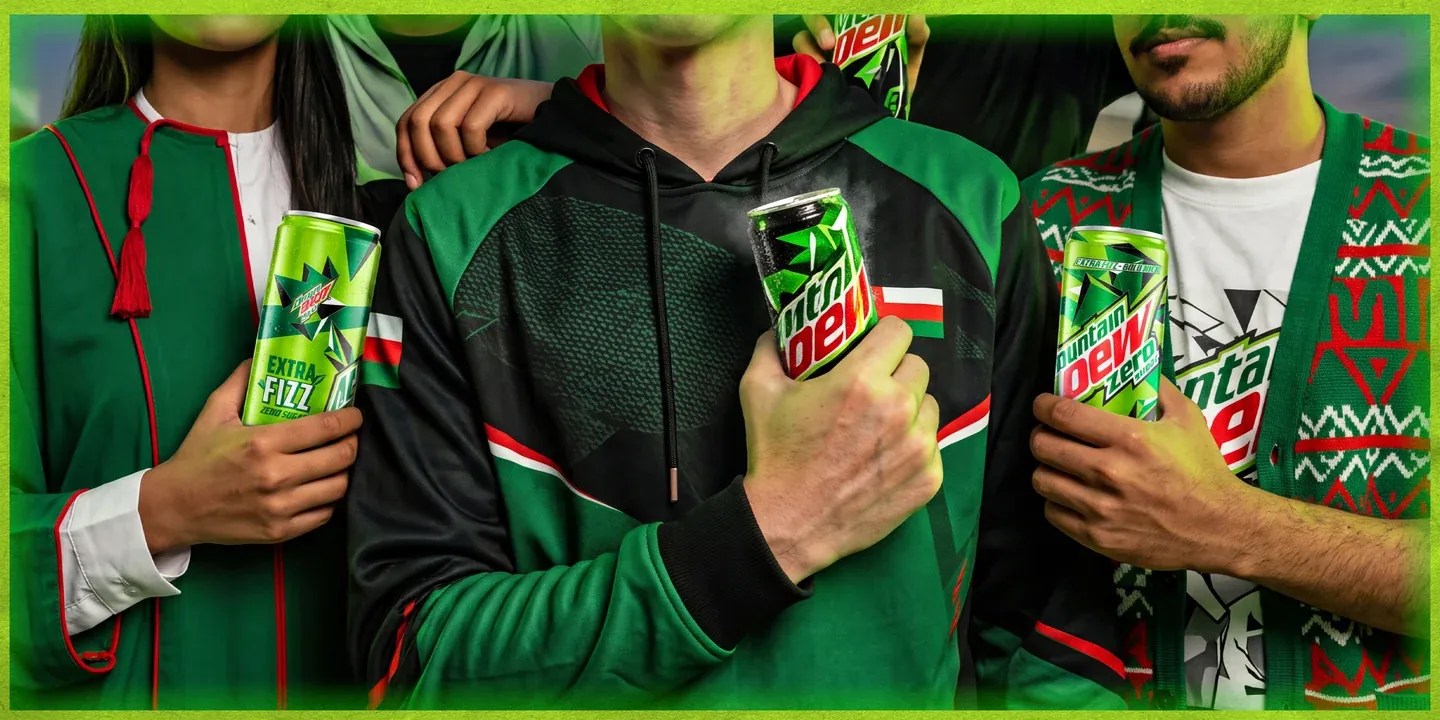 Three men in green clothing holding Mountain Dew cans in a close-cropped group portrait