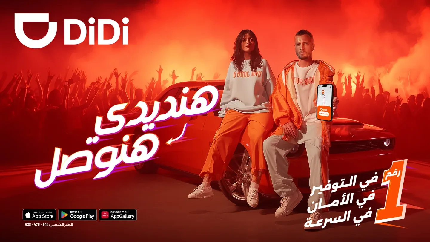 DiDi supplied AI concept with a man and woman beside a red car in orange concert lighting