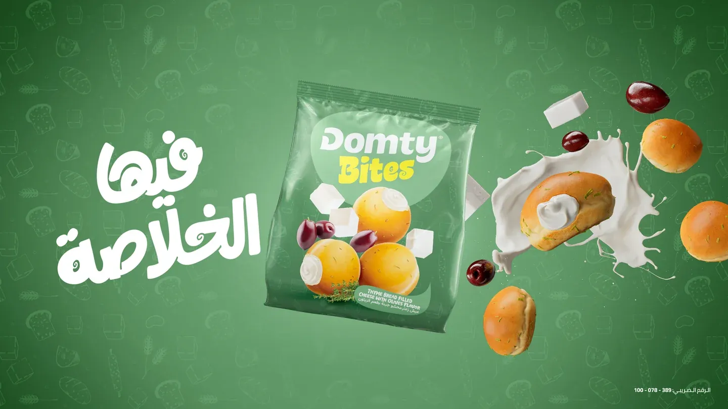 Domty Bites green pack surrounded by cheese, olives and round snacks on green